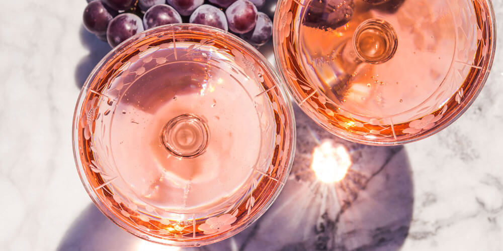 Zwei Weingläser gefüllt mit Roséwein von oben betrachtet und von der Sonne beschienen